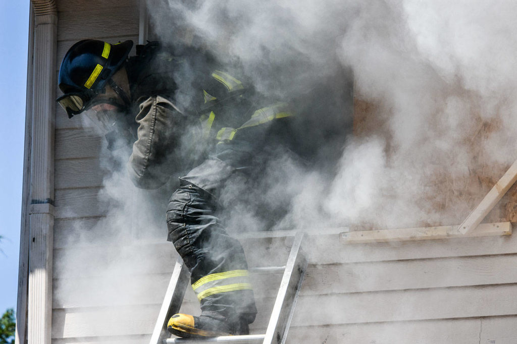 A Snohomish County fire recruit climbs from a second-story room May 23 during a drill at a vacated home north of Arlington. (Caleb Hutton / The Herald)
