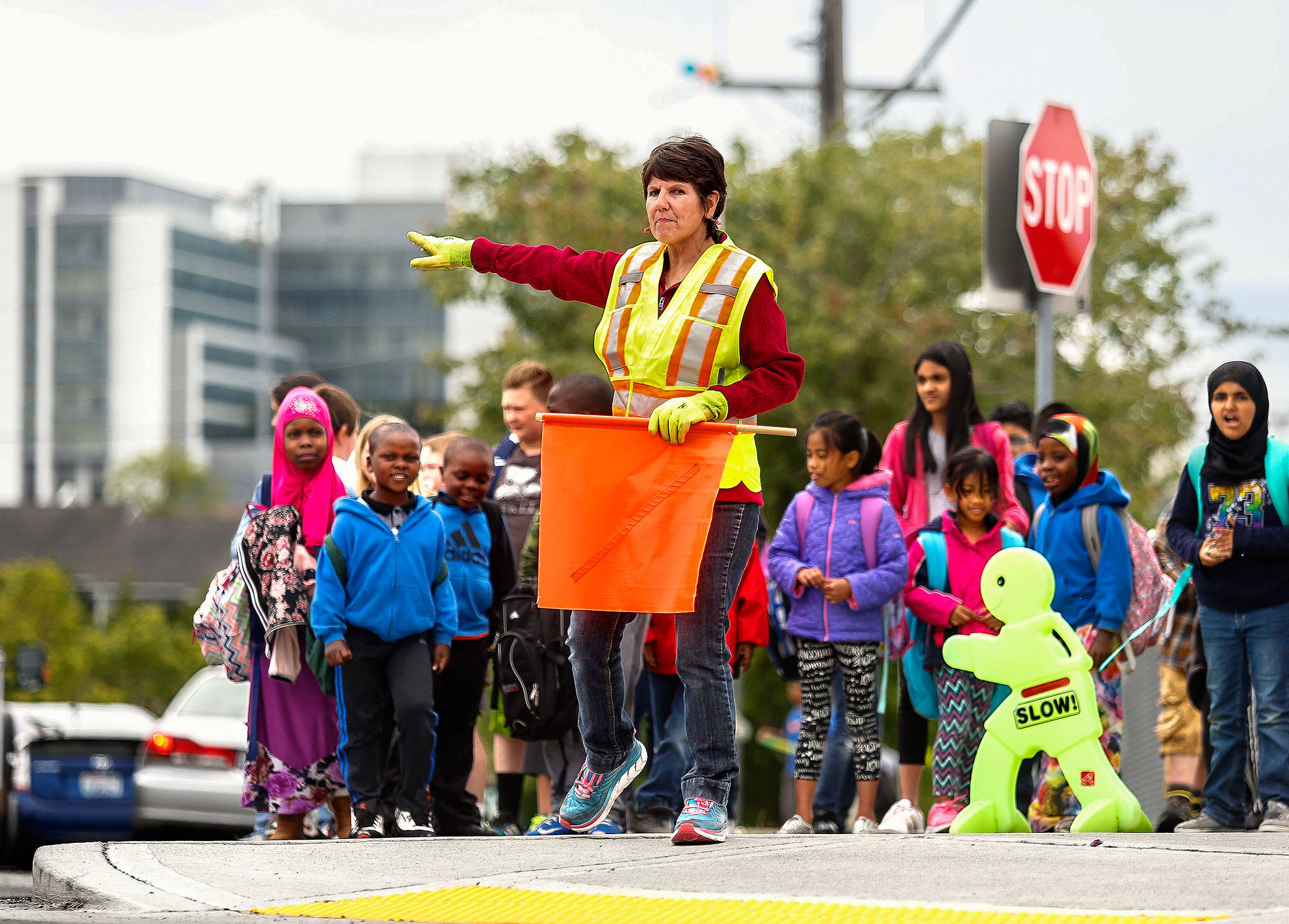 Volunteer crosswalk guard at Hawthorne Elementary School in Everett, Terri Amburgy directs cars and children waiting to cross a busy intersection adjacent to the school Tuesday, June 12. (Dan Bates / The Herald)