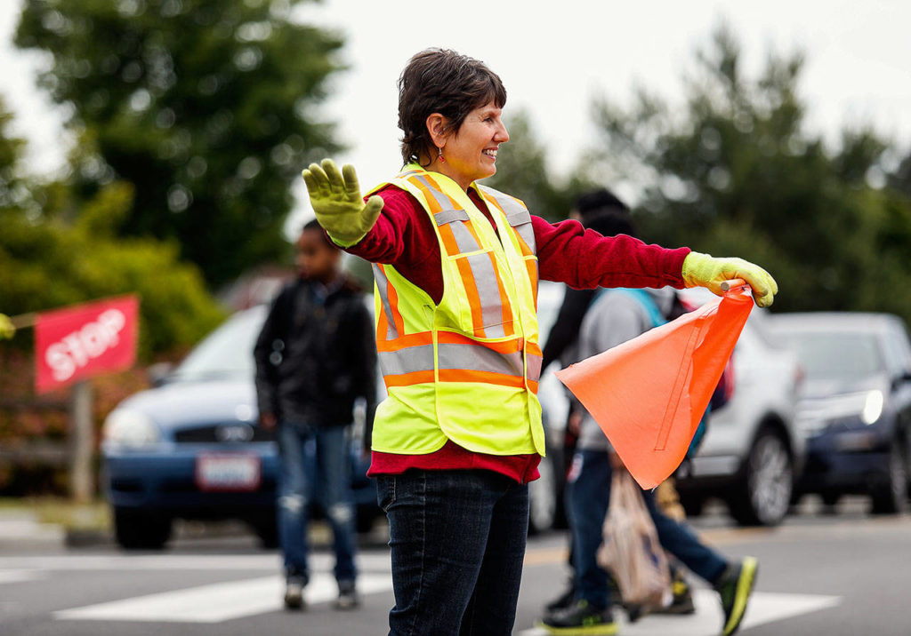 Volunteer crosswalk guard Terri Amburgy stands in the middle of a busy 4-way intersection directing cars to stay and children to walk outside Hawthorne Elementary in Everett Tuesday, June 12. (Dan Bates / The Herald)
