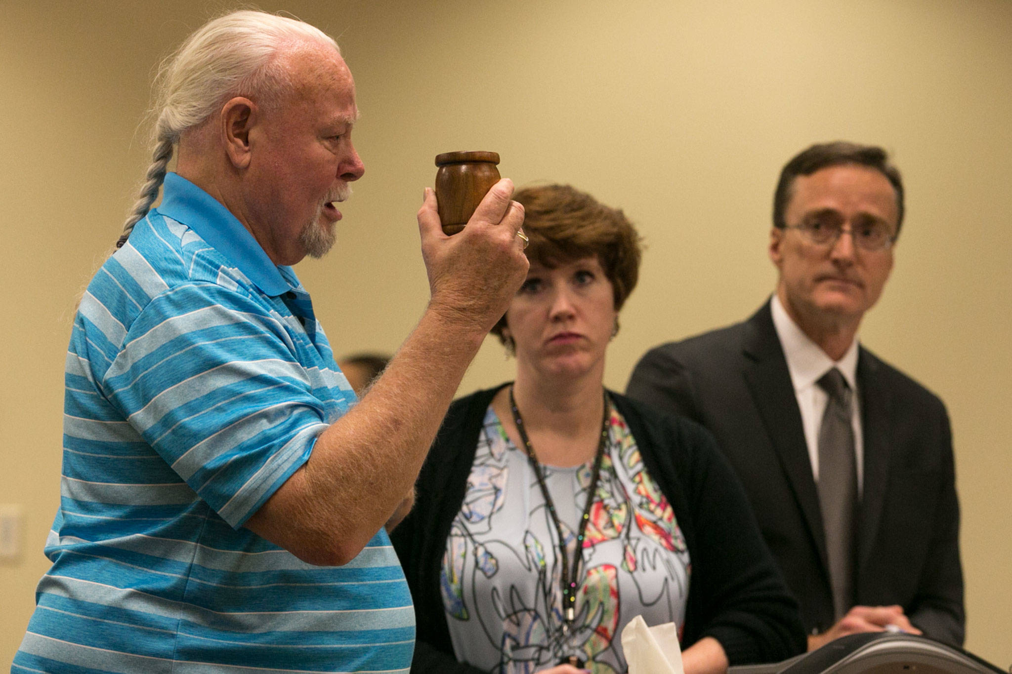 Patrick Shunn (left) holds the ashes of Monique Patenaude and his nephew and namesake, Patrick Shunn, during the sentencing of John Reed, with victim’s advocate Kameon Quillen (center) and Snohomish County chief criminal deputy prosecutor Craig Matheson, at the Snohomish County Courthouse in Everett on Friday. Reed was sentenced to life in prison for the double murder of his neighbors in Oso in 2016. (Kevin Clark / The Herald)