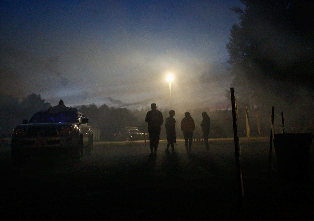 Young people walk from the fireworks field in the hazy smoke Tuesday evening. (Dan Bates / The Herald)
