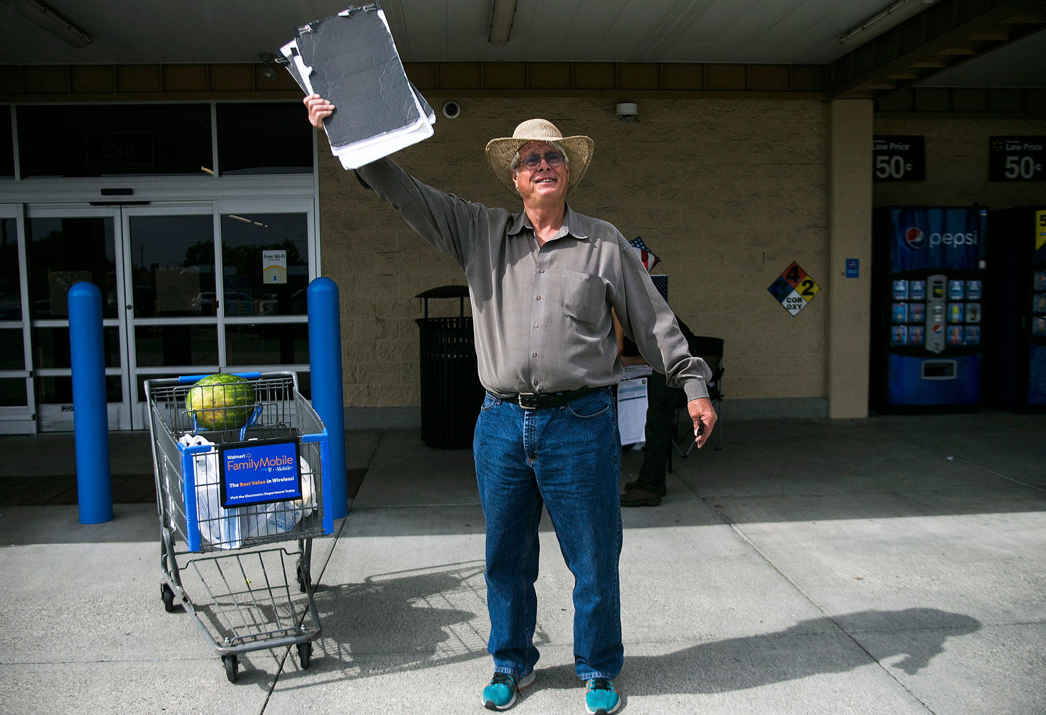 Mark Pitts waves to try to flag people down for signatures outside of Walmart last week in Everett. (Olivia Vanni / The Herald)