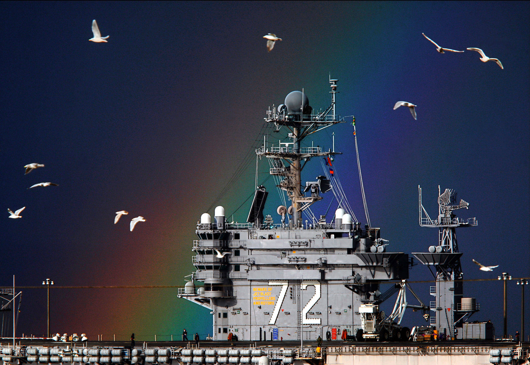 A rainbow strikes gold and gulls fill the sky near the USS Abraham Lincoln while it sits in port at Naval Station Everett on a January morning in 2010. (Dan Bates / Herald file photo)