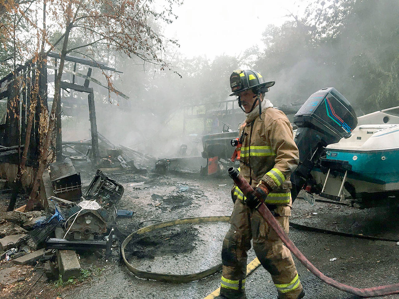 A firefighter moves through the charred debris of an extinguished garage fire Monday, July 2, north of Lynnwood. (South Snohomish Fire & Rescue)