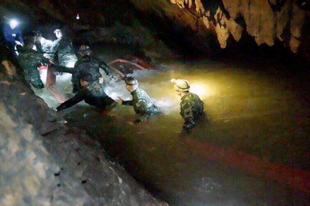 Thai rescue teams on Monday walk into a cave complex where 12 boys and their soccer coach went missing. (Tham Luang Rescue Operation Center via AP) 
