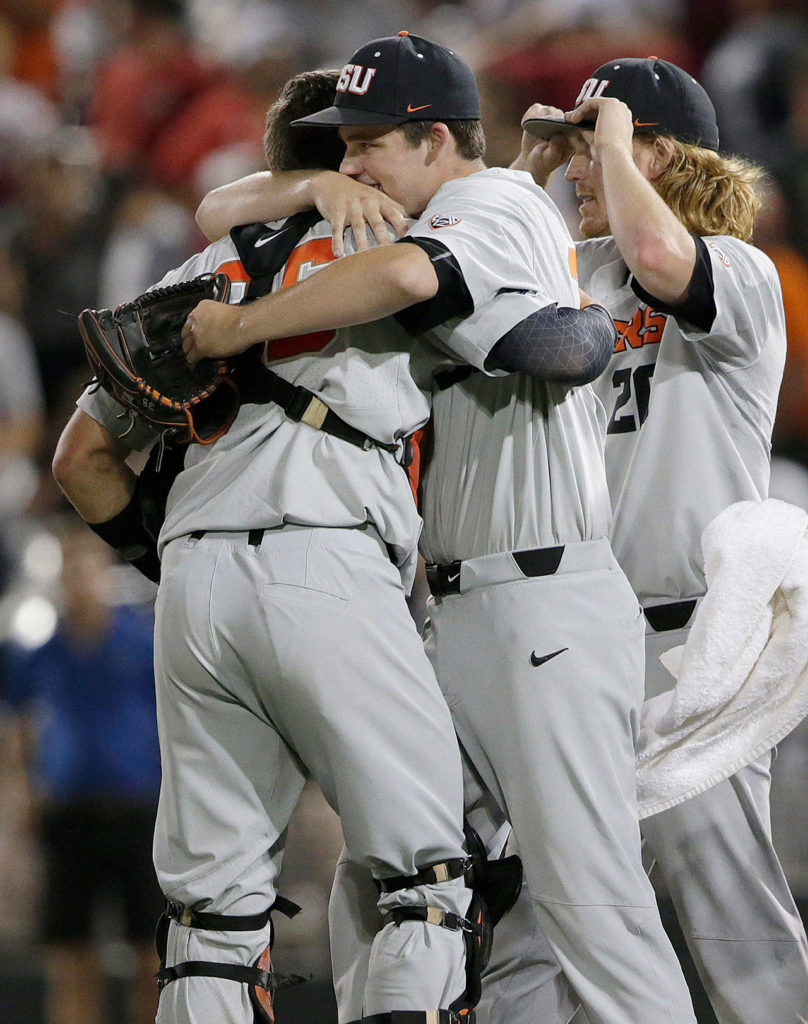 Oregon State pitcher Jake Mulholland (center), a Snohomish High School alum, celebrates with catcher Adley Rutschman after Oregon State beat Arkansas 5-3 in Game 2 of the College World Series finals on June 27, 2018, in Omaha, Neb. (AP Photo/Nati Harnik)
