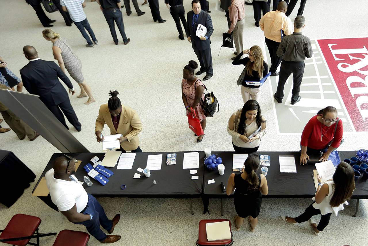 In this June 21 photo, job applicants talk with representatives from Custom Services at a job fair hosted by Job News South Florida, in Sunrise, Florida. (AP Photo/Lynne Sladky)