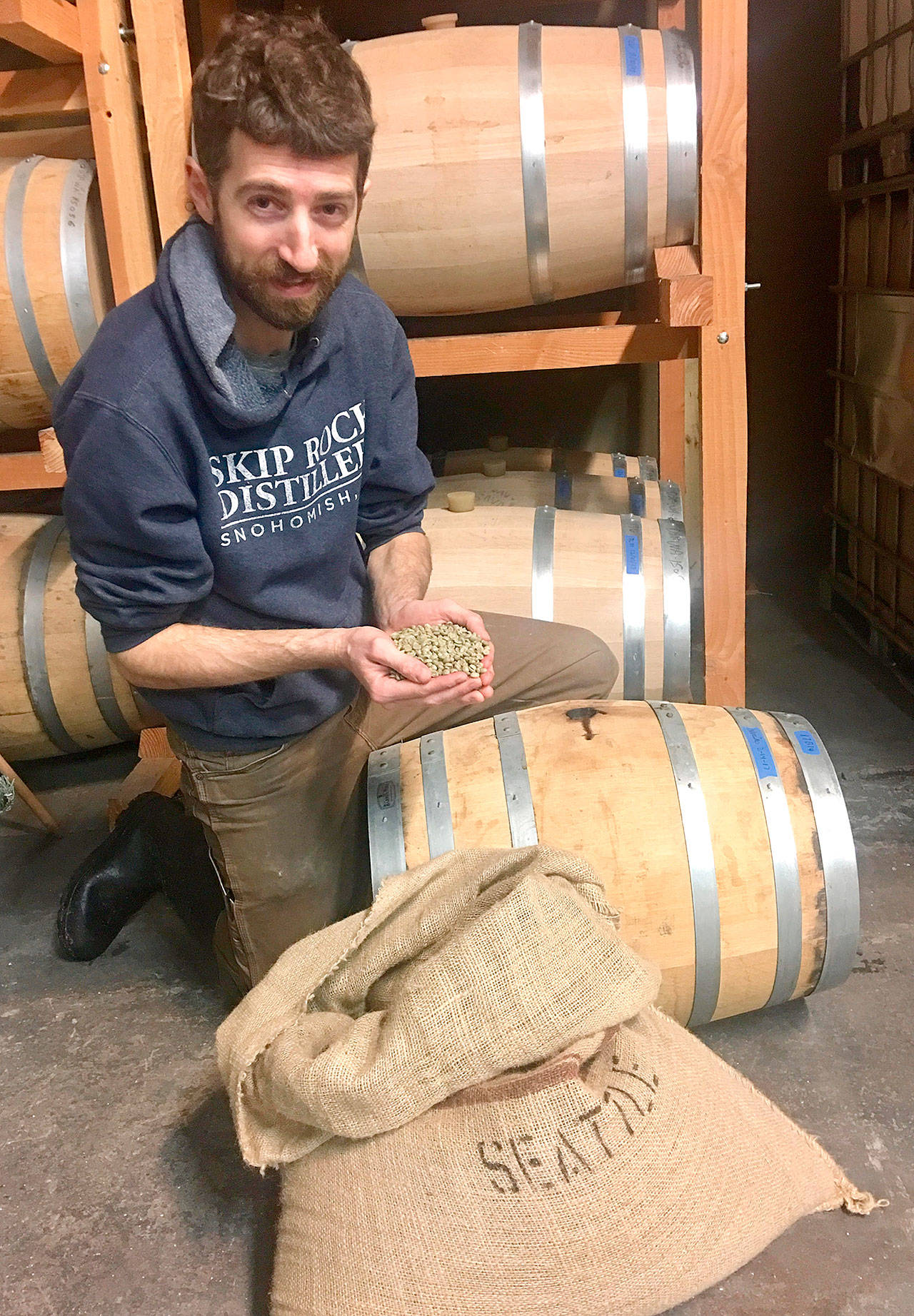 Skip Rock Distiller Production Manager Brian Roys holds the coffee beans that were rested in the distillery’s nocino barrels and eventually used to make 5 Rights’ Mr. O Coffee Oatmeal Stout anniversary beer. (Skip Rock Distillers)
