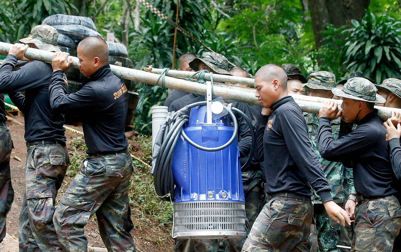 Soldiers carry a pump to help drain rising water in a cave where 12 boys and their soccer coach have been trapped since June 23 in Mae Sai, Thailand, on Friday. (AP Photo/Sakchai Lalit)
