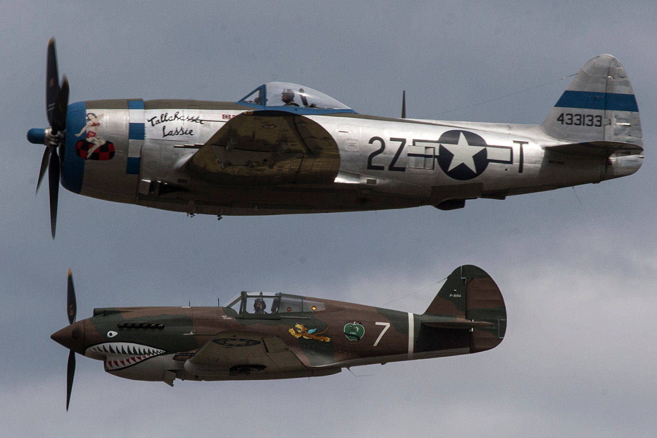 A P-47 Thunderbolt (top) passes a P-40 Tomahawk during maneuvers at the 50th annual Arlington Fly-In at the Arlington Airport on Saturday. (Andy Bronson / The Herald)