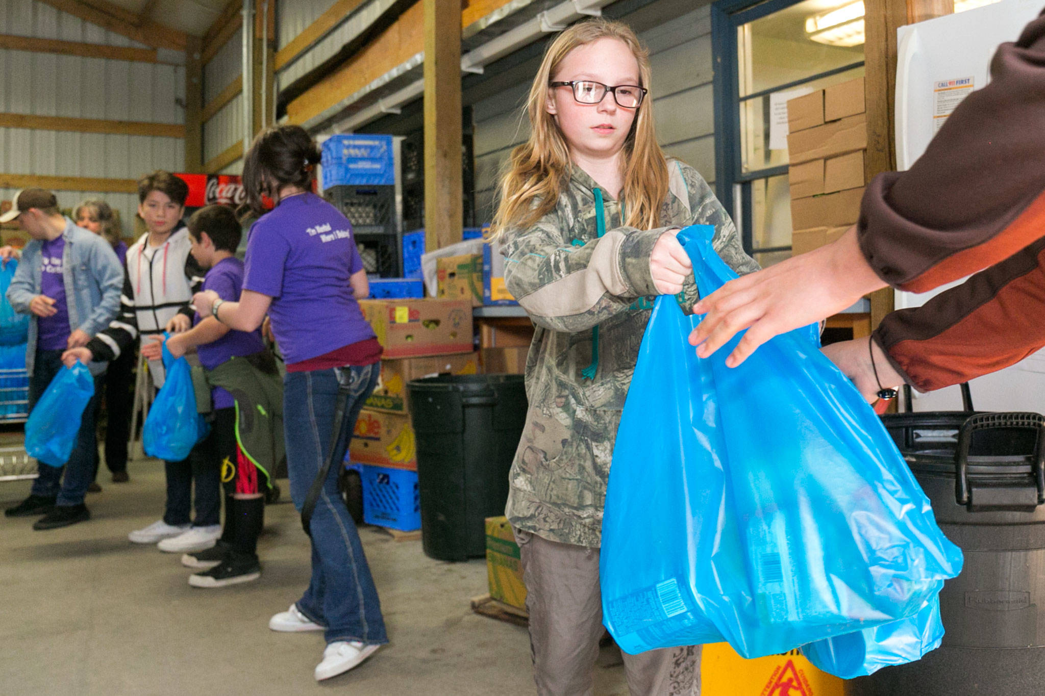 Taylor Webster hands off a bag of food stuffs at the Sultan Food Bank on March 14 as part of a Sky Valley Youth Coalition project focused on childhood hunger. (Kevin Clark / Herald file photo)