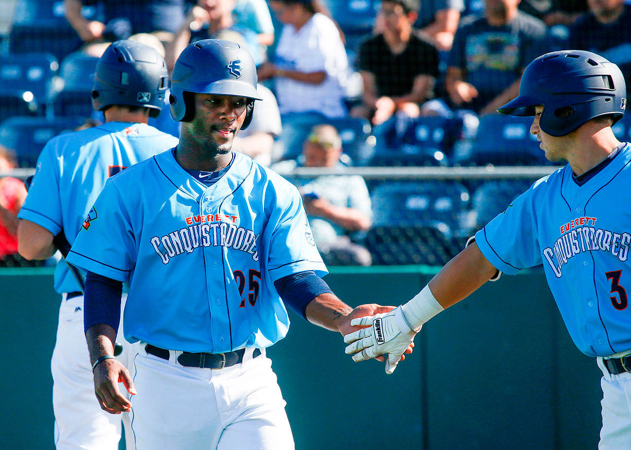 The AquaSox’ Josh Stowers (25) gets a hand from teammate Bobby Honeyman after scoring a run during a game against Tri-City on June 24, 2018, at Everett Memorial Stadium. (Andy Bronson / The Herald)