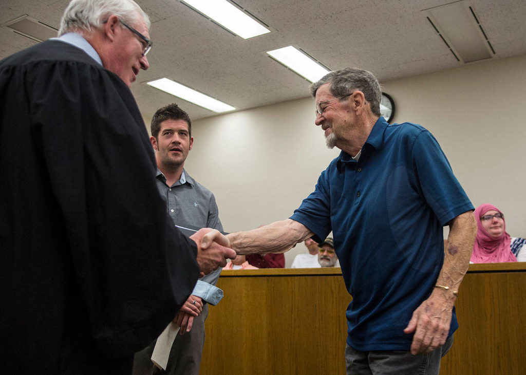 Judge Wilson shakes Rory Bossard’s hand as his son, Eric Bossard, graduates drug court at the Snohomish County Superior Court on Friday in Everett. (Olivia Vanni / The Herald)
