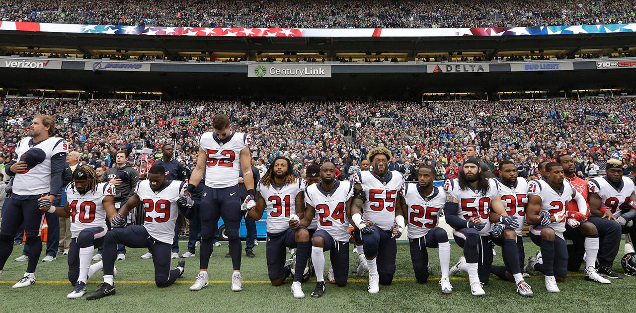 Houston Texans players kneel and stand during the singing of the national anthem before an NFL game against the Seattle Seahawks in October in Seattle. The NFL Players Association has filed a grievance with the league challenging its national anthem policy. (AP Photo/Elaine Thompson, File)