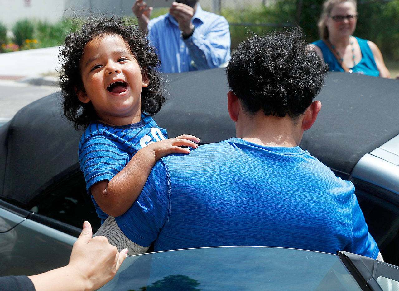 Ever Reyes Mejia, of Honduras, carries his son to a vehicle after being reunited and released by United States Immigration and Customs Enforcement in Grand Rapids, Michigan, on Tuesday. Two boys and a girl who had been in temporary foster care in Grand Rapids were reunited with their Honduran fathers after they were separated at the U.S.-Mexico border about three months ago. (AP Photo/Paul Sancya)