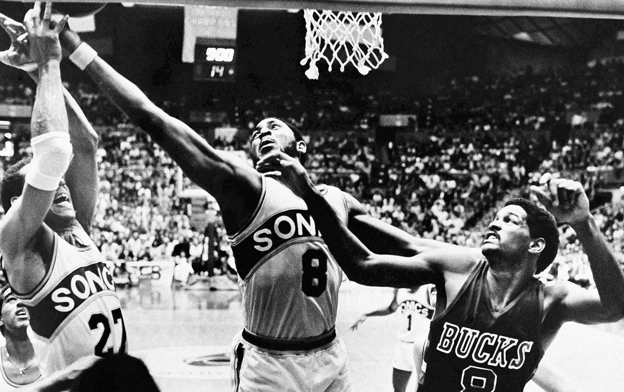 The Supersonics’ Lonnie Shelton (8) reaches for a rebound along with teammate John Johnson (27) as the Bucks’ Marques Johnson (8) looks on during a playoff game on April 20, 1980, Seattle. (AP Photo/Grant M. Haller)