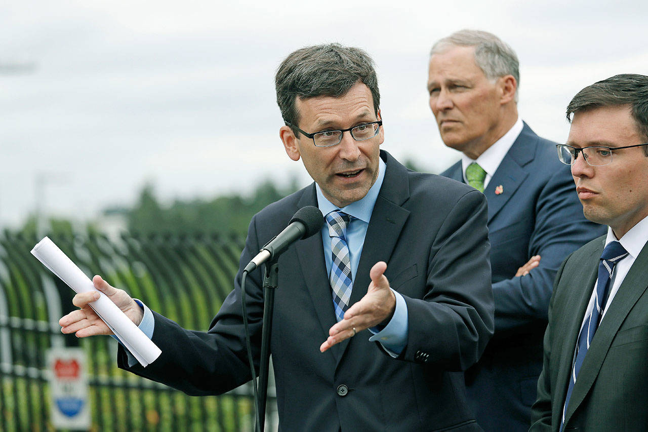 Washington state Attorney General Bob Ferguson speaks as Washington Gov. Jay Inslee (center) and Solicitor General Noah Purcell look on at a news conference in SeaTac on June 21. Seven national fast-food chains have agreed to end policies that block workers from changing branches under the threat of legal action from the state of Washington. Ferguson announced the binding agreements Thursday with companies including Arby’s, Jimmy John’s and Cinnabon. (AP Photo/Elaine Thompson, File)