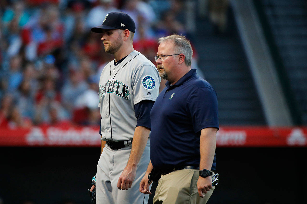 Mariners starting pitcher James Paxton (left) and a Seattle trainer walk off the field after he was relieved during the first inning of a game against the Angels on July 12, 2018, in Anaheim, Calif. (AP Photo/Jae C. Hong)