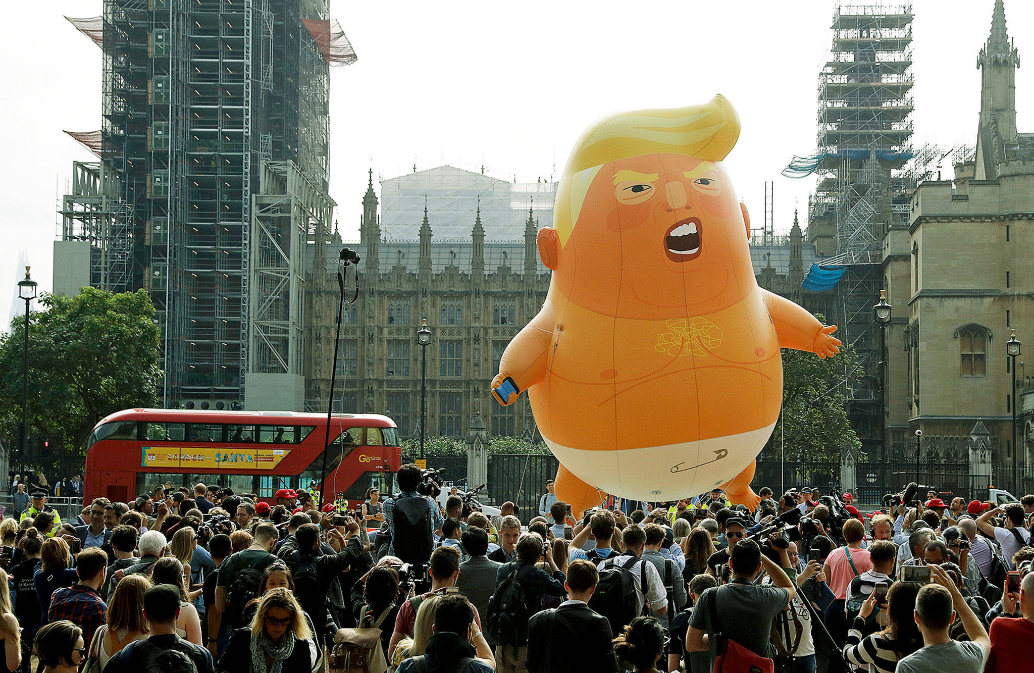 A cartoon balloon depicting U.S. President Donald Trump rises above the crowd near the scaffolded Houses of Parliament and Big Ben in London on Friday. (AP Photo/Matt Dunham)