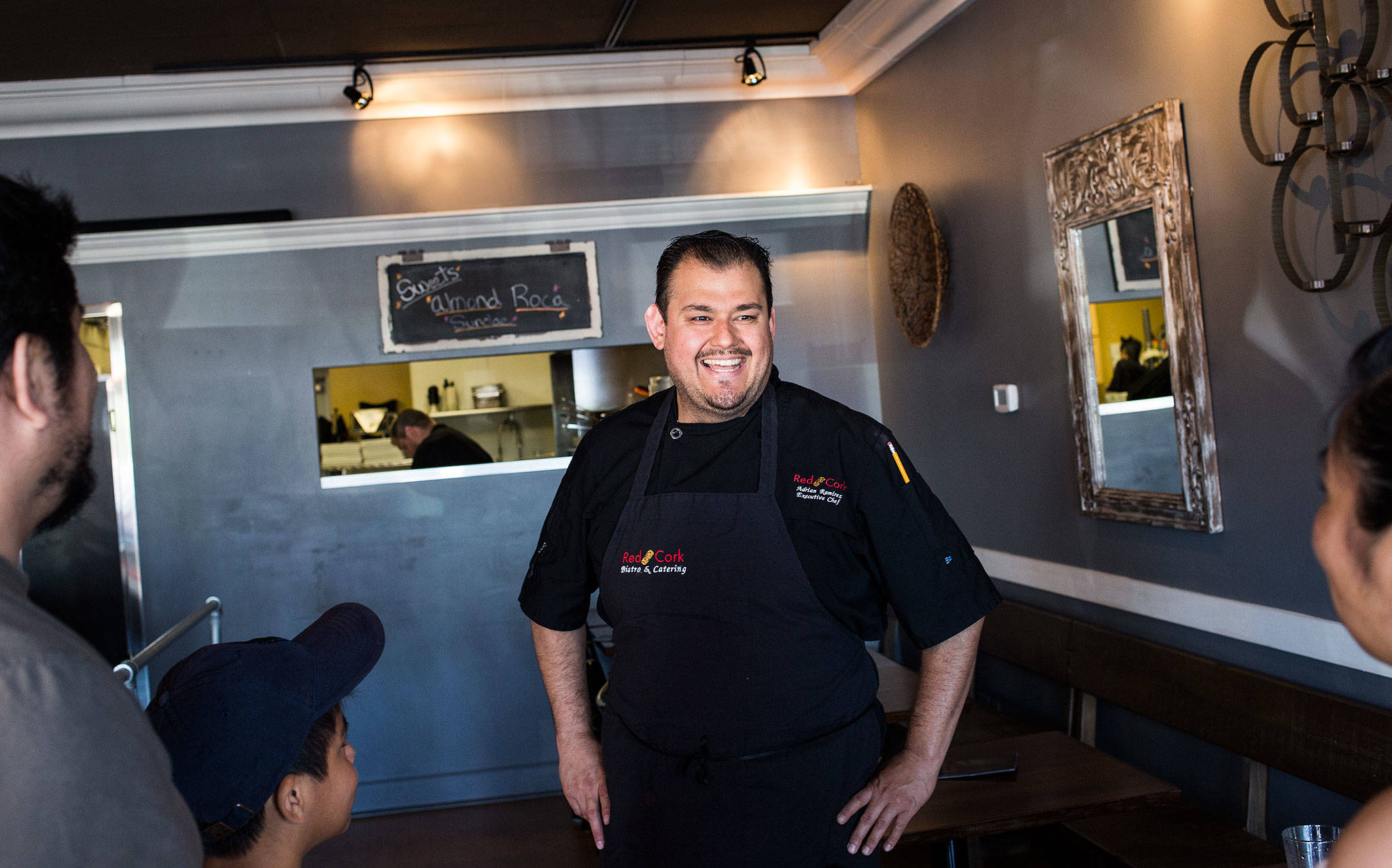 Former Sno-Isle Tech culinary student Adrian Ramirez laughs with customers at Red Cork Bistro in Mukilteo. Ramirez co-owns Red Cork Bistro with his wife, Soco Molina. (Andy Bronson / The Herald)