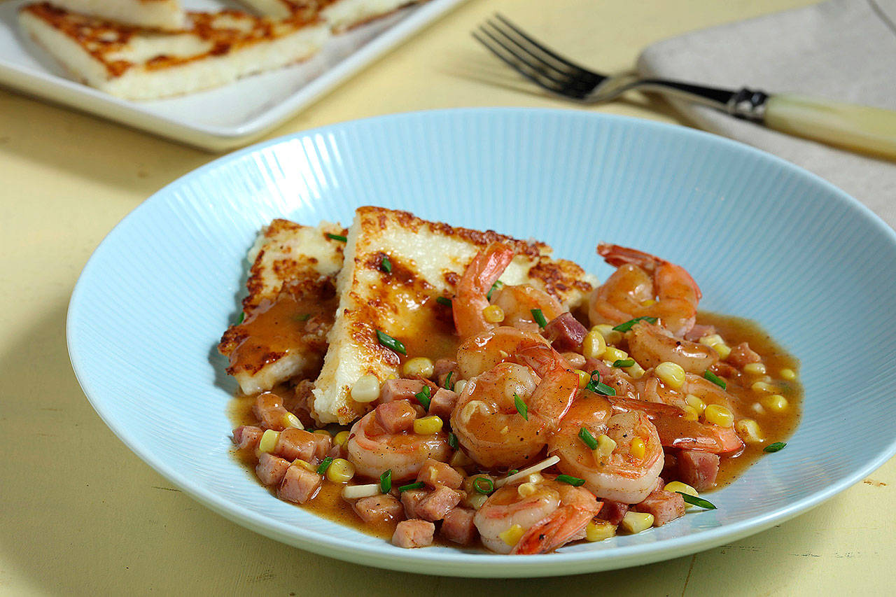 Grits are formed into cakes, then crisped in a skillet to serve as a bed for a savory mix of ham, shrimp and corn. (Abel Uribe/Chicago Tribune)