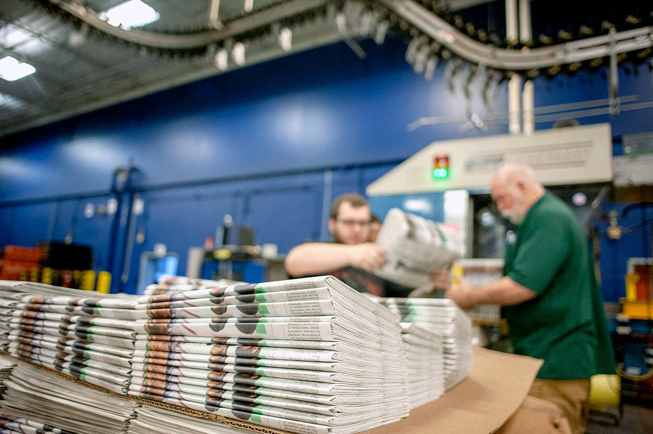 Production workers stack newspapers at the Janesville Gazette Printing & Distribution plant in Janesville, Wisconsin. Members of Congress are warning that newspapers in their home states are in danger of cutting coverage or going out of business if the U.S. maintains recently imposed tariffs on Canadian newsprint. (Angela Major/The Janesville Gazette via AP)