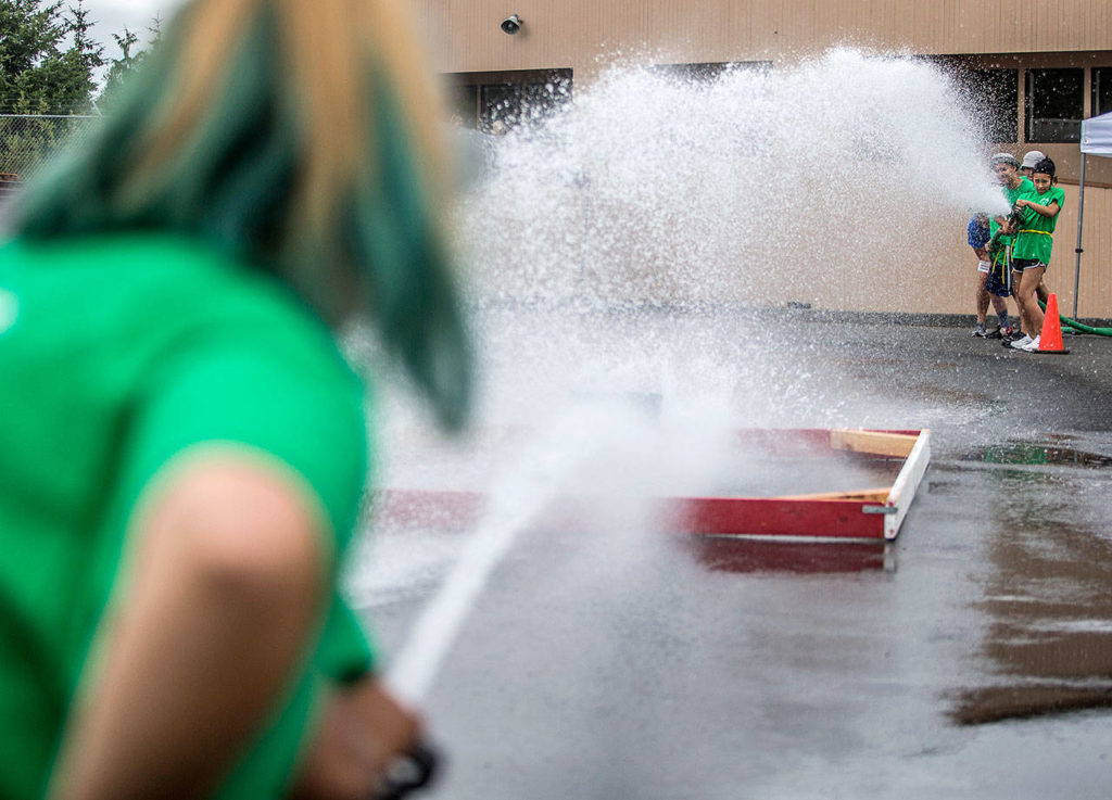 Campers duel during a fire hose game during Kids Fire Camp at South County Fire Administrative Headquarters on Wednesday in Everett. (Olivia Vanni / The Herald)
