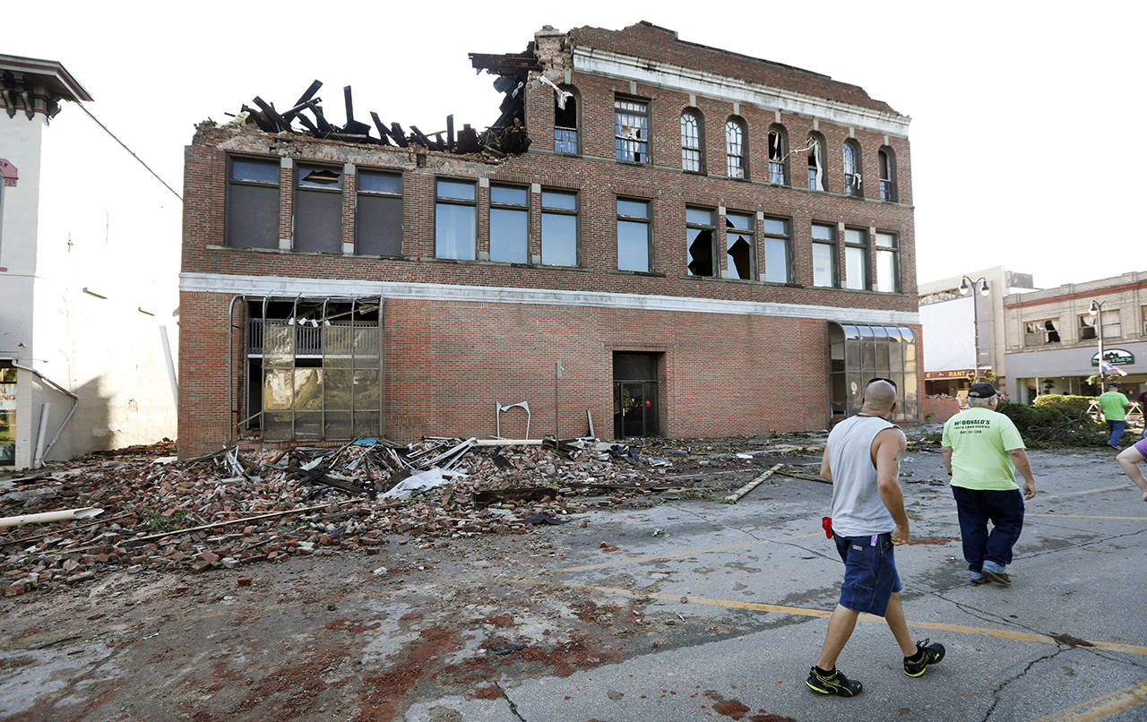 Local residents walk past a tornado-damaged building on Main Street on Thursday in Marshalltown, Iowa. (AP Photo/Charlie Neibergall)