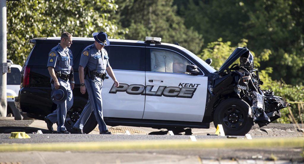 Washington State patrolmen investigate the scene where a Kent police officer was killed while trying to deploy spike strips in an effort to stop a fleeing driver early Sunday in Kent. (Bettina Hansen/The Seattle Times via AP)
