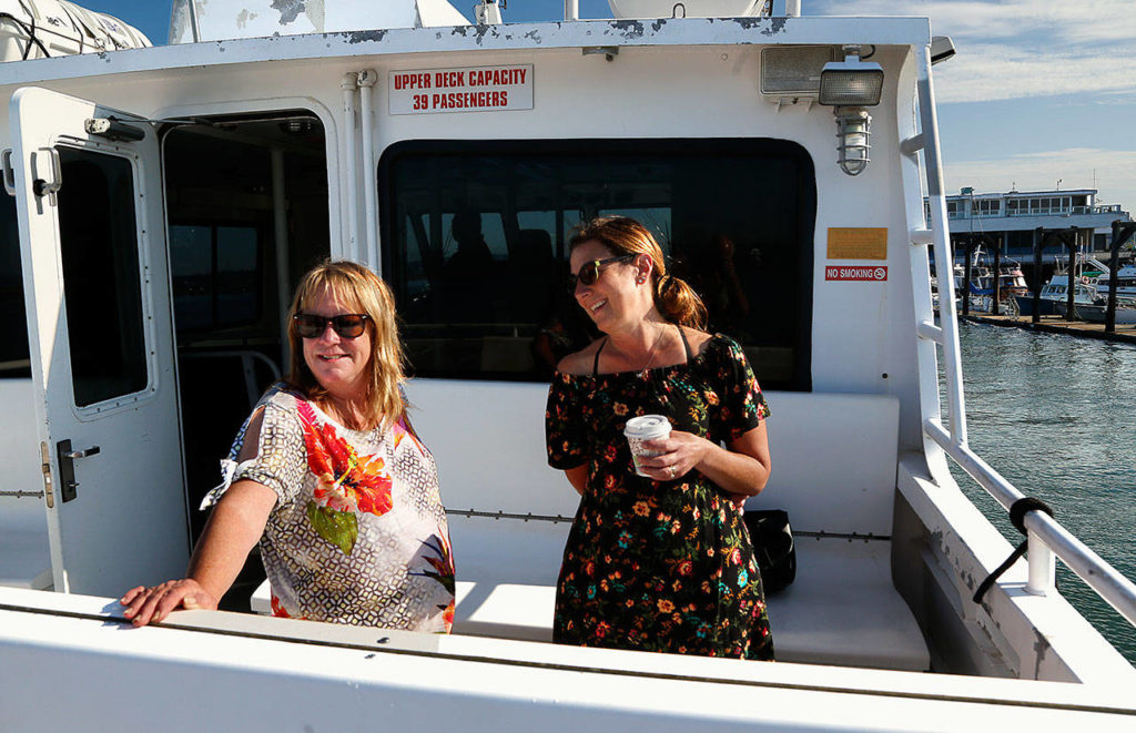 Hat Island harbormaster Barb Conwell (left) and Michelle Brown, a “snow bird” who splits her time between Hat Island and Arizona, share a laugh aboard the Hat Express, a private ferry that connects the island with Everett. Michelle’s husband John Brown does maintenance on the island. (Dan Bates / Herald Photographer)
