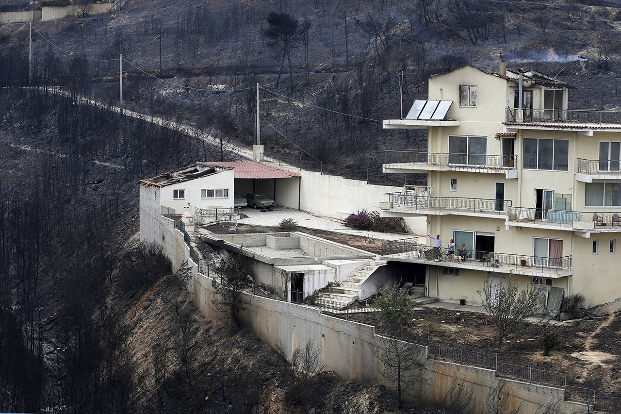 People look the burned forest from their balcony in Neos Voutzas, east of Athens, on Tuesday. (AP Photo/Thanassis Stavrakis)