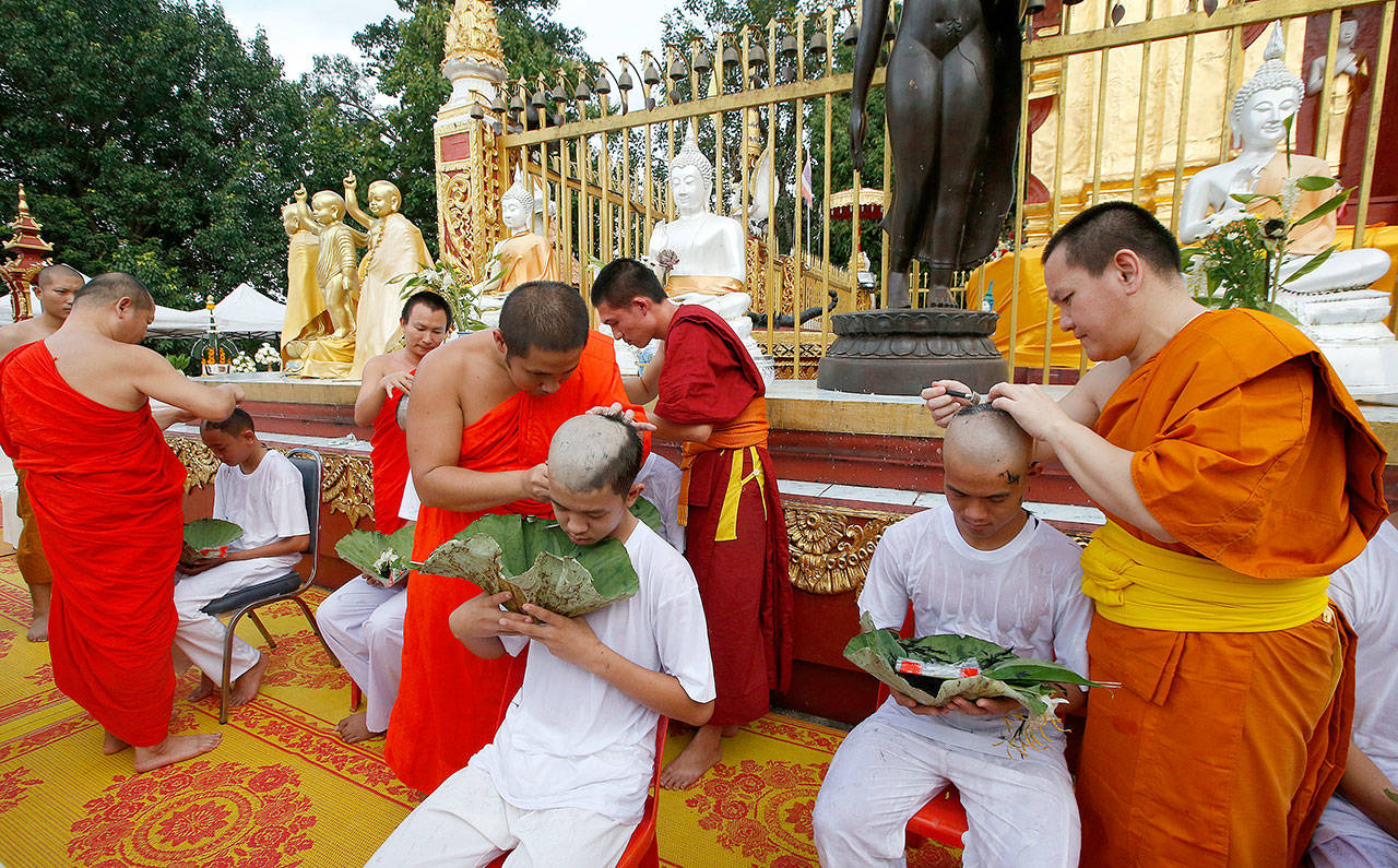 Soccer coach Ekkapol Chantawong (right) and members of the team who were rescued last week from a flooded cave have their heads shaved in a traditional Buddhist ceremony in Mae Sai district, Chiang Rai province, northern Thailand, on Tuesday,. The young soccer teammates and their coach who have rescued from the cave in northern Thailand took part in a Buddhist ceremony Tuesday as they prepared to be ordained to become Buddhist novices and monks. (Sakchai Lalit / Associated Press)