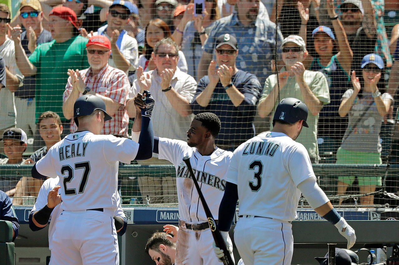 Seattle’s Ryon Healy (27) is greeted at the home dugout by Dee Gordon (center) after Healy’s solo home run during the second inning of the Mariners’ 3-2 win over San Francisco on Wednesday in Seattle. (AP Photo/Ted S. Warren)
