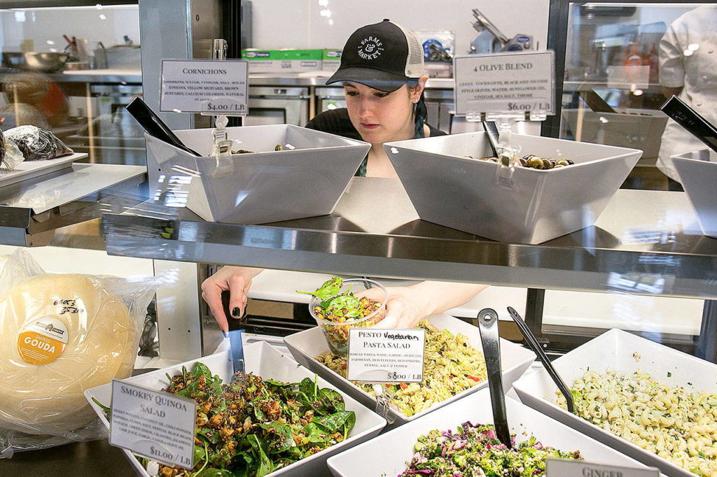 April Stair packages smokey quinoa salad at Farms & Market in Everett. (Kevin Clark / The Herald)
