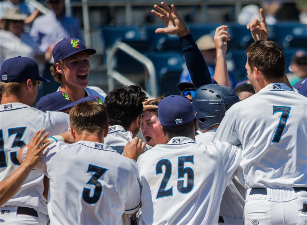 The AquaSox celebrate and pat their teammate Troy Dixon on the head after his game winning home run during the game against Vancouver at Everett Memorial Stadium on Thursday, July 26, 2018 in Everett, Wa. (Olivia Vanni / The Herald)
