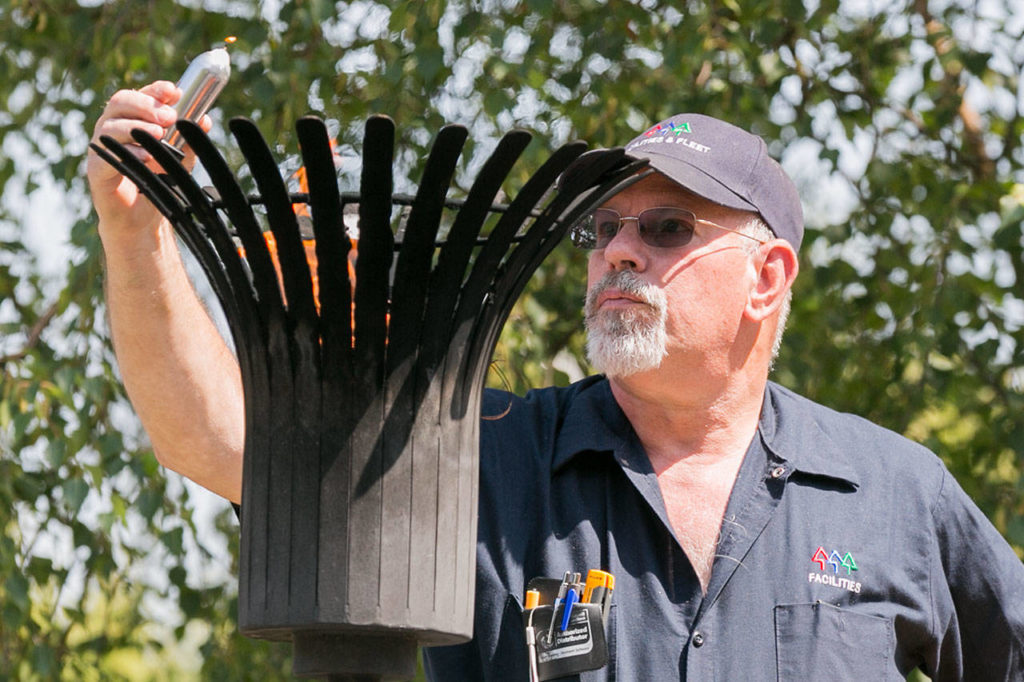 Steven Slawson lights a candle from the eternal flame Friday afternoon during the decommissioning of the Snohomish County Courthouse Veteran Memorial in Everett. (Kevin Clark / The Herald)
