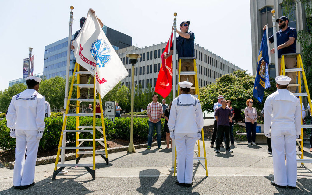 Naval personnel wait for flags to be lowered Friday afternoon during the decommissioning of the Snohomish County Courthouse Veteran Memorial in Everett. (Kevin Clark / The Herald)
