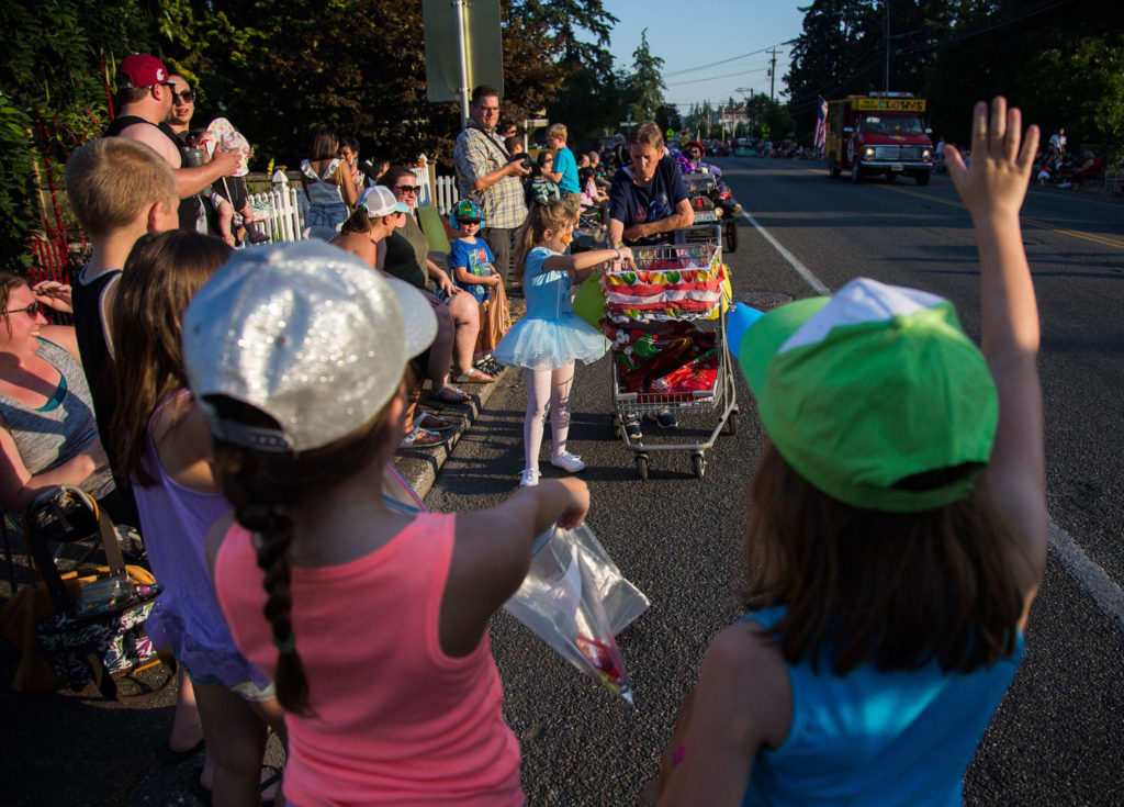 Children wave as candy is handed out during the Tour de Terrace parade on Friday, July 27, 2018 in Mountlake Terrace, Wa. (Olivia Vanni / The Herald)
