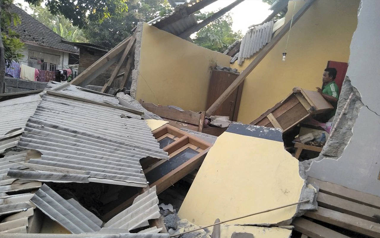In this image made from video, a man inspects the damage caused by an early morning earthquake on the island of Lombok, Indonesia, on Sunday. (Indonesia’s Disaster Mitigation Agency via AP)