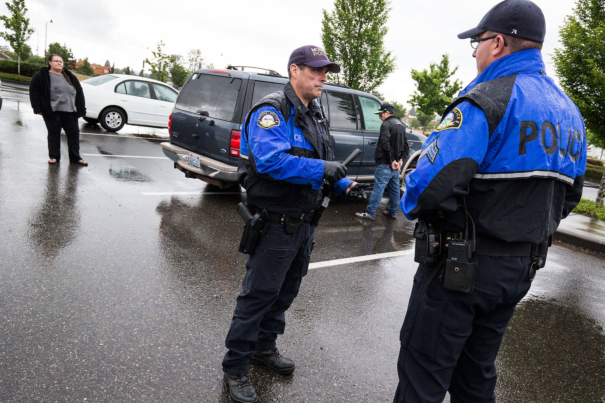 After a man, at center right, was spotted leaving with a possibly stolen item at Lowe’s, Monroe Police officer Scott Kornish, center left, talks with Sgt. Paul Ryan on Wednesday, June 13, 2018, in Monroe. Two suspects were detained and not taken to jail, but the car was impounded. (Andy Bronson / The Herald)