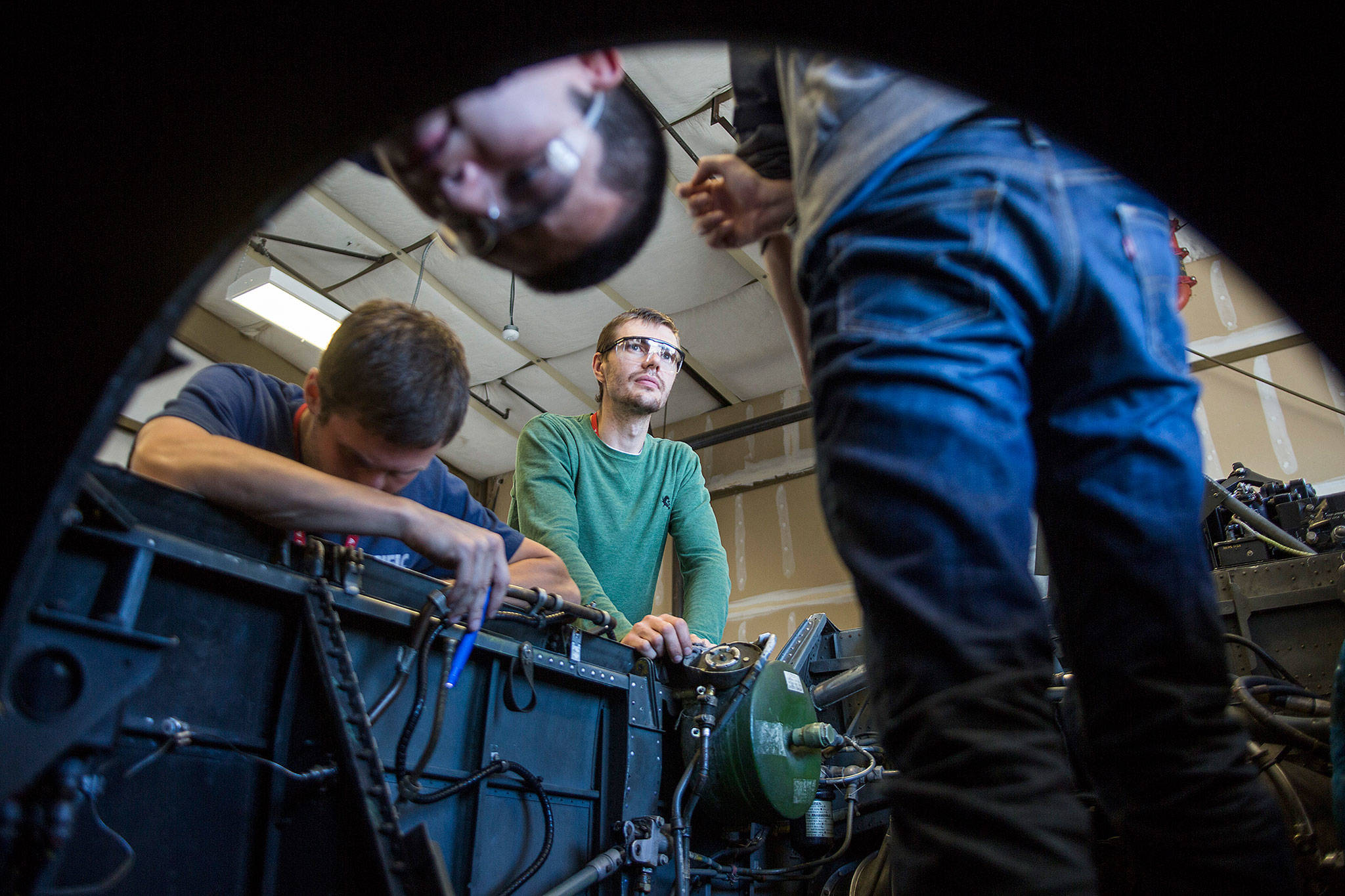 Alexey Ryabinin, center, looks up while his fellow classmates inspect the interior of a BAC Jet Provost that they removed a Viper engine from during class at Everett Community College’s Aviation Maintenance Technician School on Friday, July 13, 2018 in Everett, Wa. (Olivia Vanni / The Herald)
