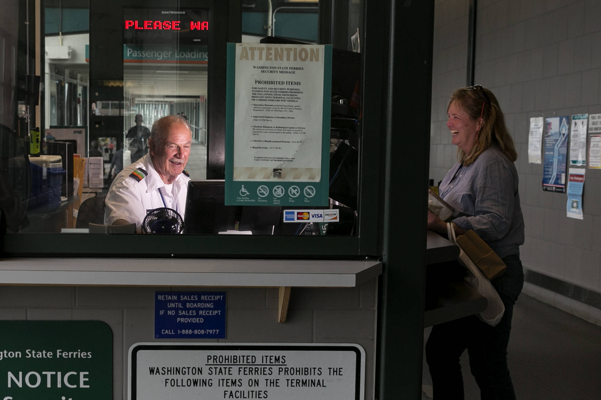 Steve Jackson shares a laugh with a ferry passenger at the Edmonds ferry terminal. (Kevin Clark / The Herald)