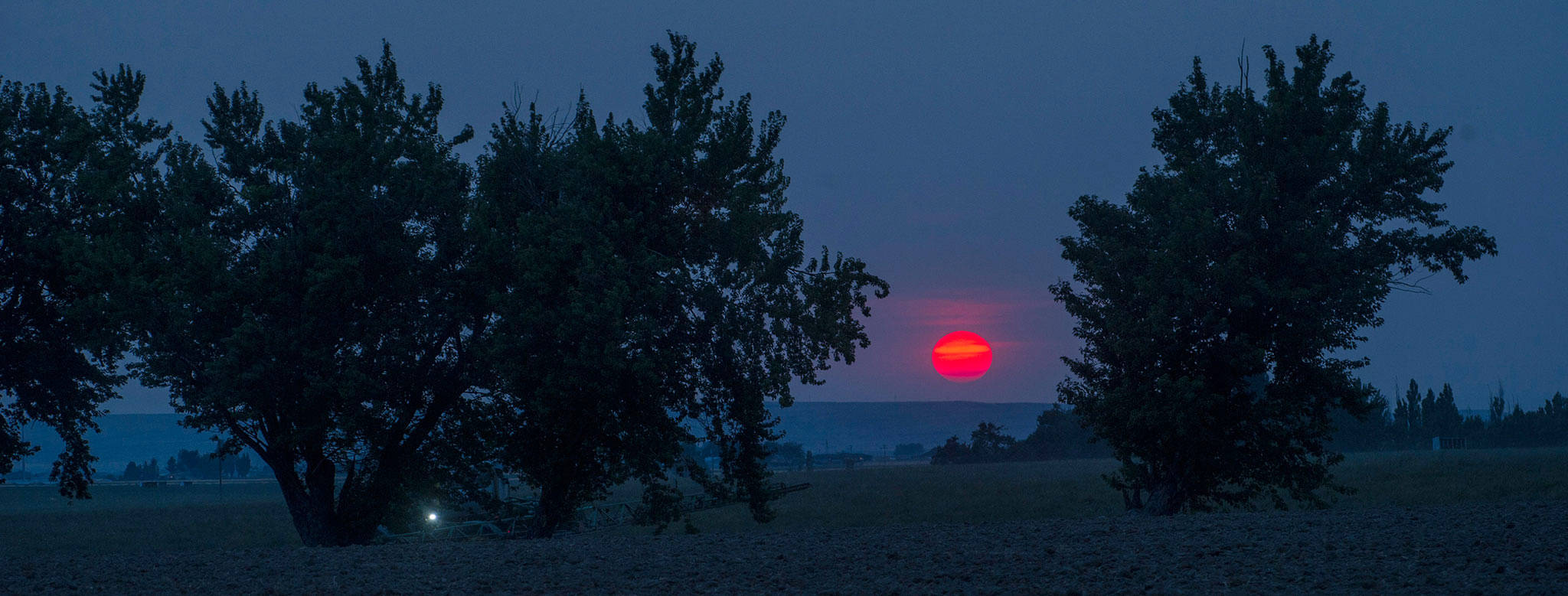 In this Monday photo, with a sky full of wildfire smoke and haze, the sun set bright red south of Touchet, Washington. (Greg Lehman/Walla Walla Union-Bulletin via AP)