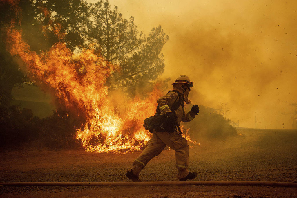 A firefighter runs while trying to save a home as a wildfire tears through Lakeport, California, on Tuesday. (AP Photo/Noah Berger)

