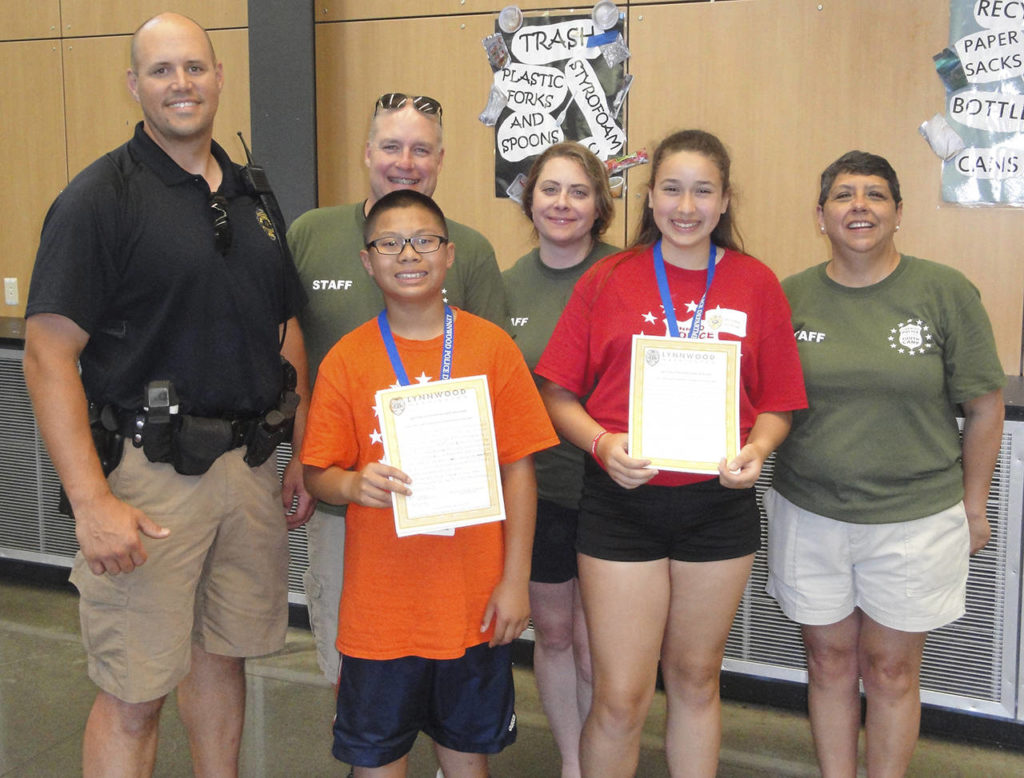 Community Health & Safety Sgt. Cole Langdon, Patrol Sgt. Dave Byrd, Victim Services Coordinator Tiffany Krusey and Police Camp Coordinator Connie Avalos-Galer pose with Arthur Jordan (AJ) Pidlaoan, 11 (in orange T-shirt), and Alondra Guitron, 13 (in red T-shirt). AJ and Alondra were recognized at the end of camp for their outstanding “Why I Want to Attend Police Camp” letters. (Submitted photo)
