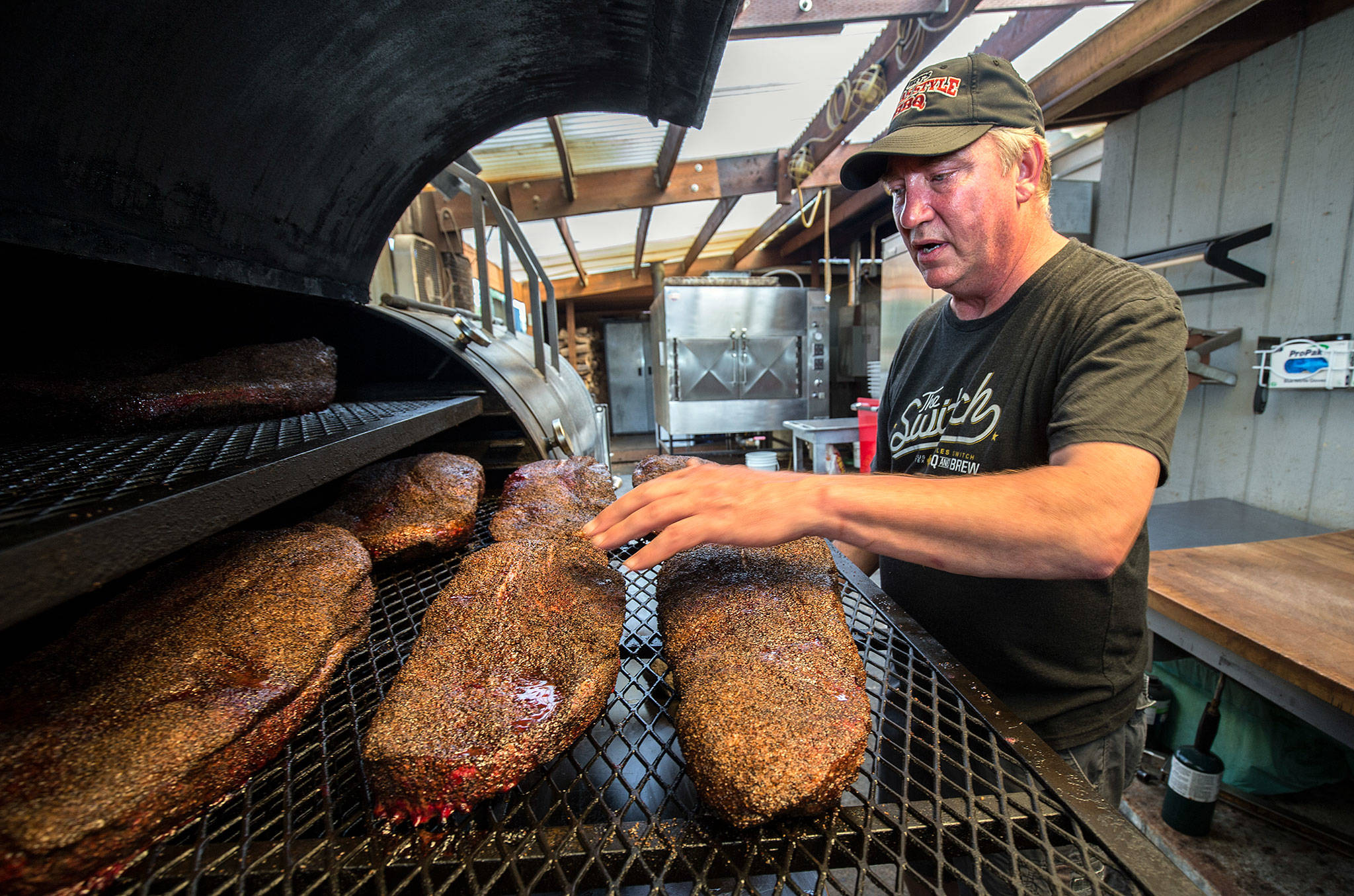 Jeff Knoch, owner of Jeff’s Texas Style BBQ in Marysville, checks on a row of briskets in a smoker. Food & Wine named the restaurant the best barbecue in the state. (Andy Bronson / The Herald)