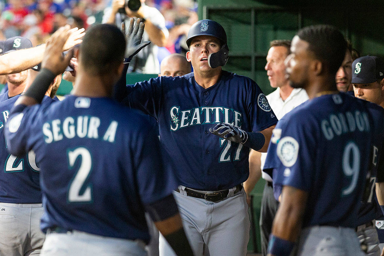 Seattle’s Ryon Healy (27) is congratulated by teammates after scoring a run during the sixth inning of the Mariners’ 4-3 win over Texas in 12 innings Monday night in Arlington, Texas. (AP Photo/Sam Hodde)