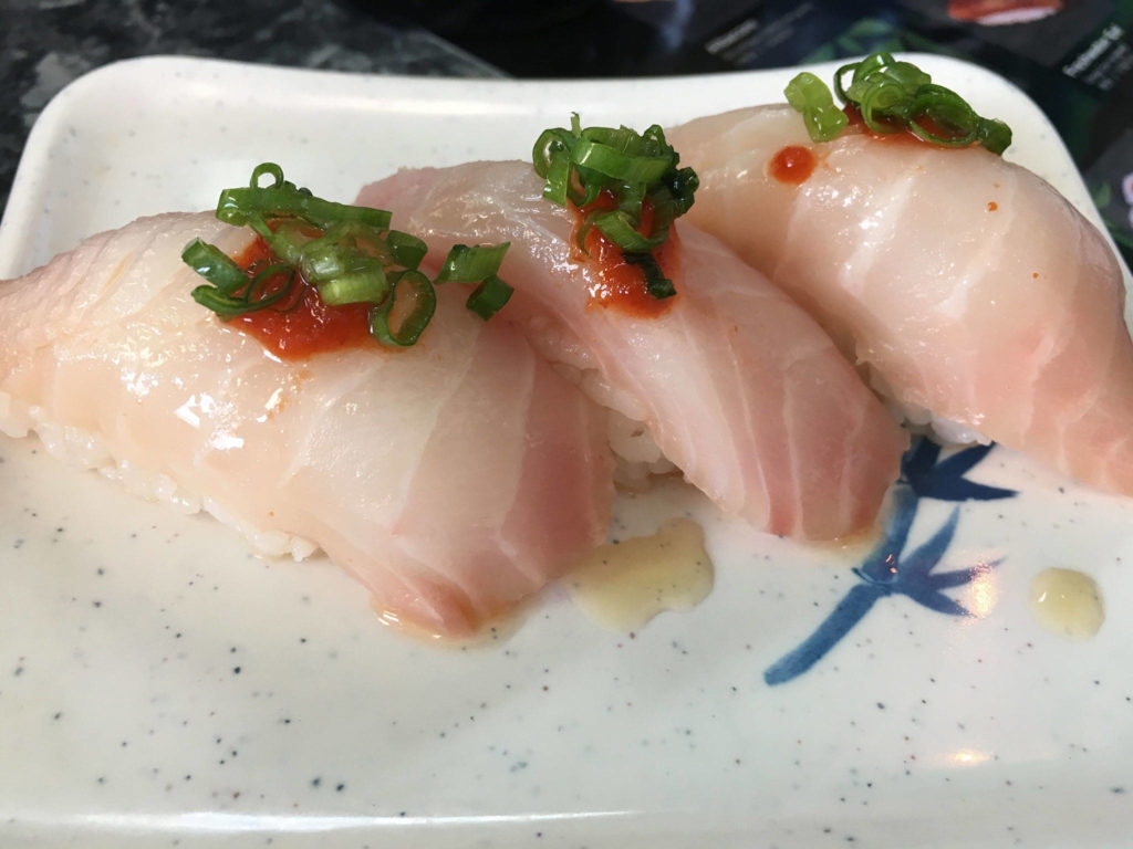Red snapper nigiri comes garnished with green onion slices and a slightly spicy chili oil at Sushi Ring in Everett. (Ben Watanabe / The Herald)
