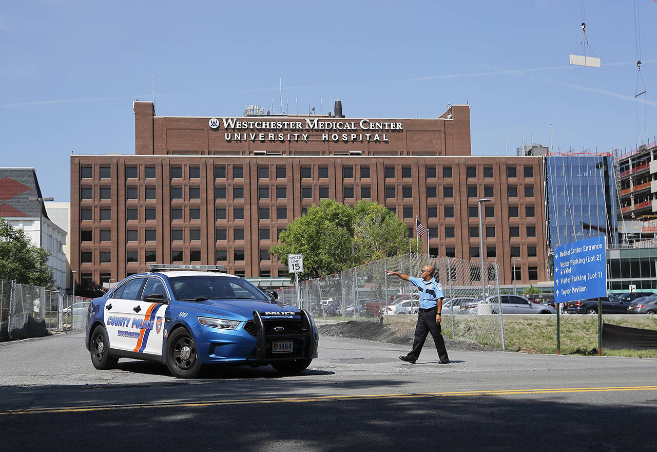 A Westchester Medical Center security guard directs traffic as a Westchester County police car pulls out of the drive to the main entrance of the hospital, Wednesday in Valhalla, New York. A man shot a female patient and then killed himself at the suburban New York hospital Wednesday, police said. (AP Photo/Julie Jacobson)