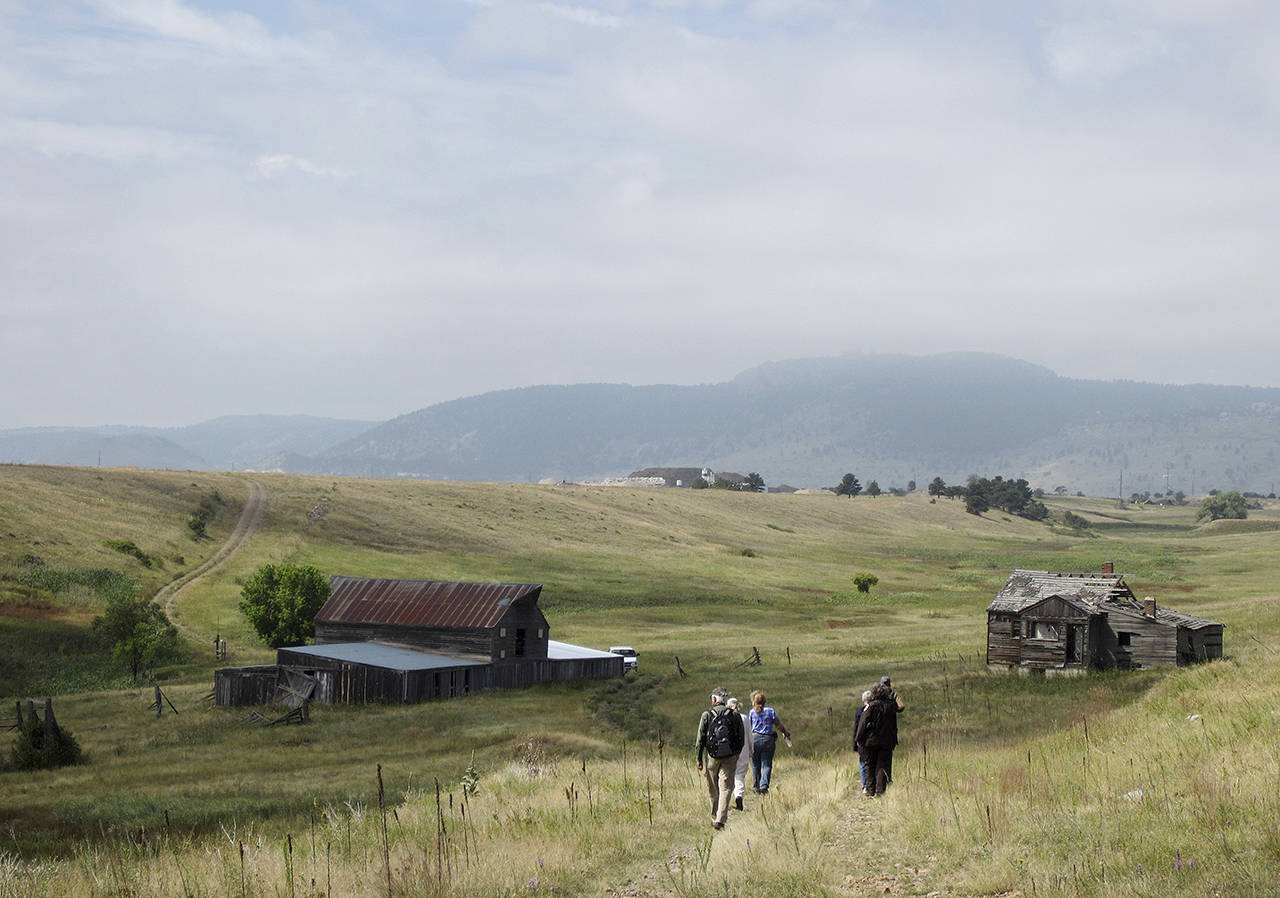 In this 2017 photo, visitors approach a former ranch house and barn during a guided hike on the Rocky Flats National Wildlife Refuge near Denver. (AP Photo/Dan Elliott, File)